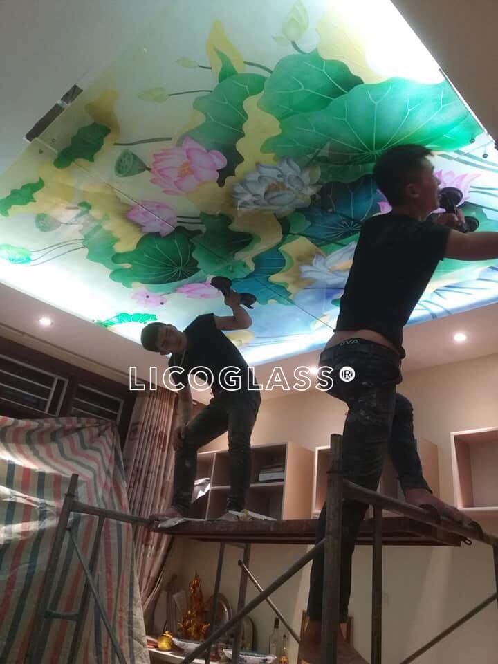 Thi công vách ốp trần bằng kính cường lực điêu khắc hoa sen 3D, dưới ánh đèn hình ảnh bông hoa hiện lên thật lung linh, ấn tượng, mang lại vẻ đẹp nổi bật cao cấp cho không gian căn phòng tranh kính